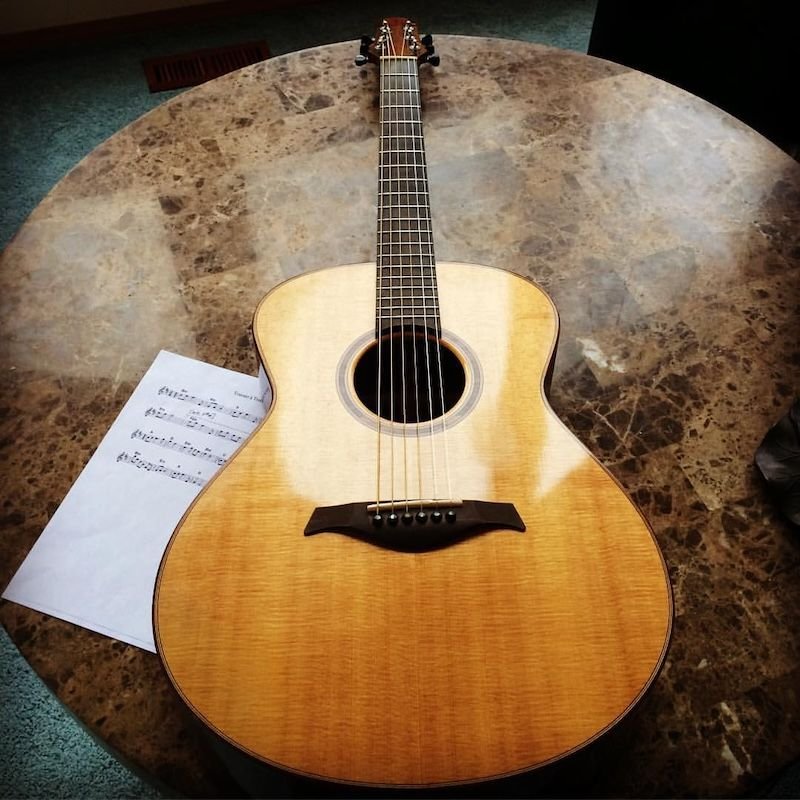 Acoustic guitar on a table with sheet music